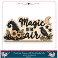 The image is a wooden sign with the text "Magic in the air" and decorative elements such as a witch's hat, flowers, and a bird.