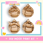 The image is a DIY wood paint kit featuring four wooden ornaments with various designs, including a reindeer, a cat, a snowman, and a rainbow.