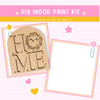 The image is a DIY wood paint kit advertisement, featuring a wooden sign with the word "HOME" and various decorative elements such as hearts and stars.