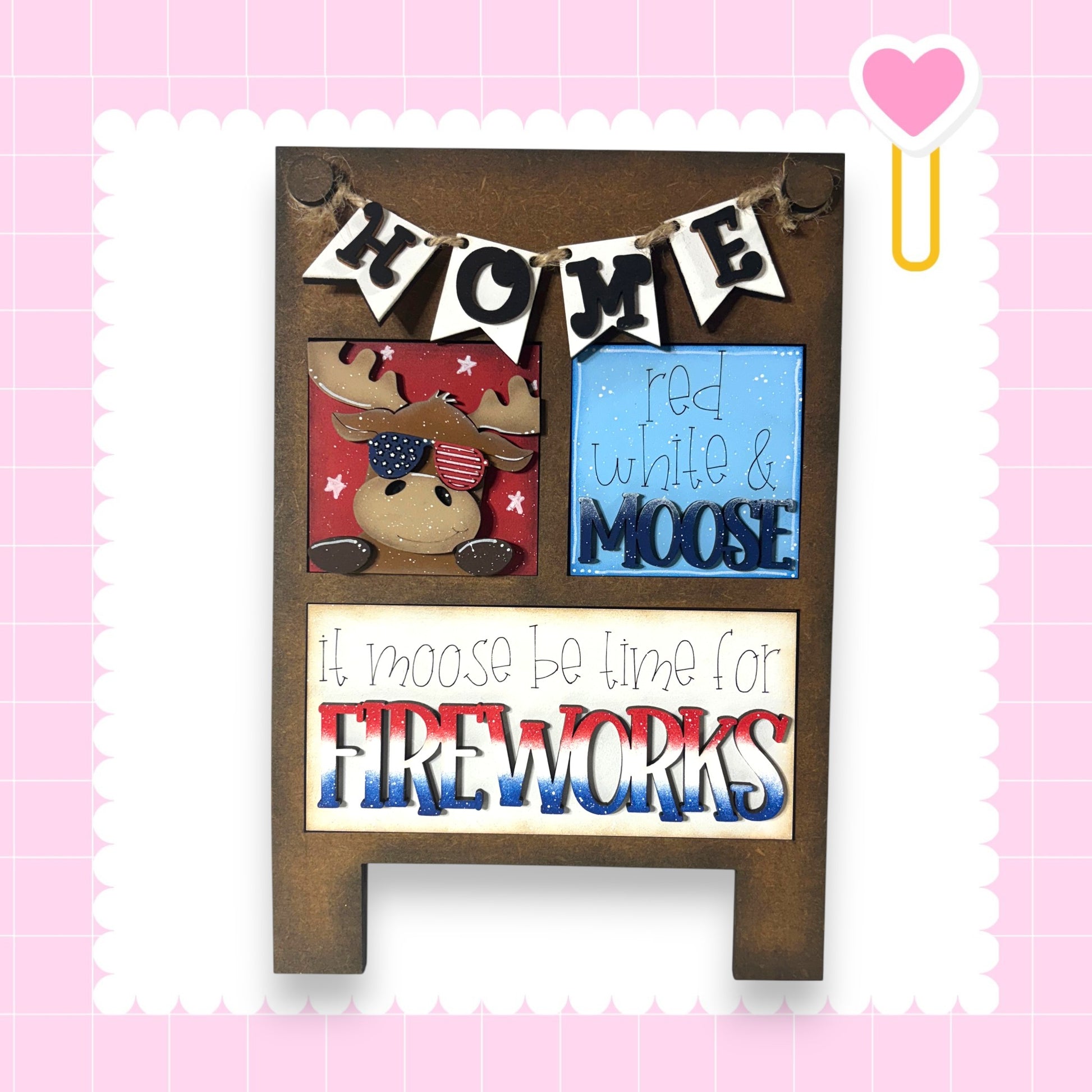 The image is a wooden sign with a moose and fireworks, accompanied by the text "Home" and "It moose be time for fireworks".