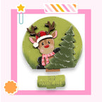 A cartoon reindeer wearing a Santa hat and scarf is holding a Christmas tree, with the text "DEER CROSSING AHEAD" below the tree.