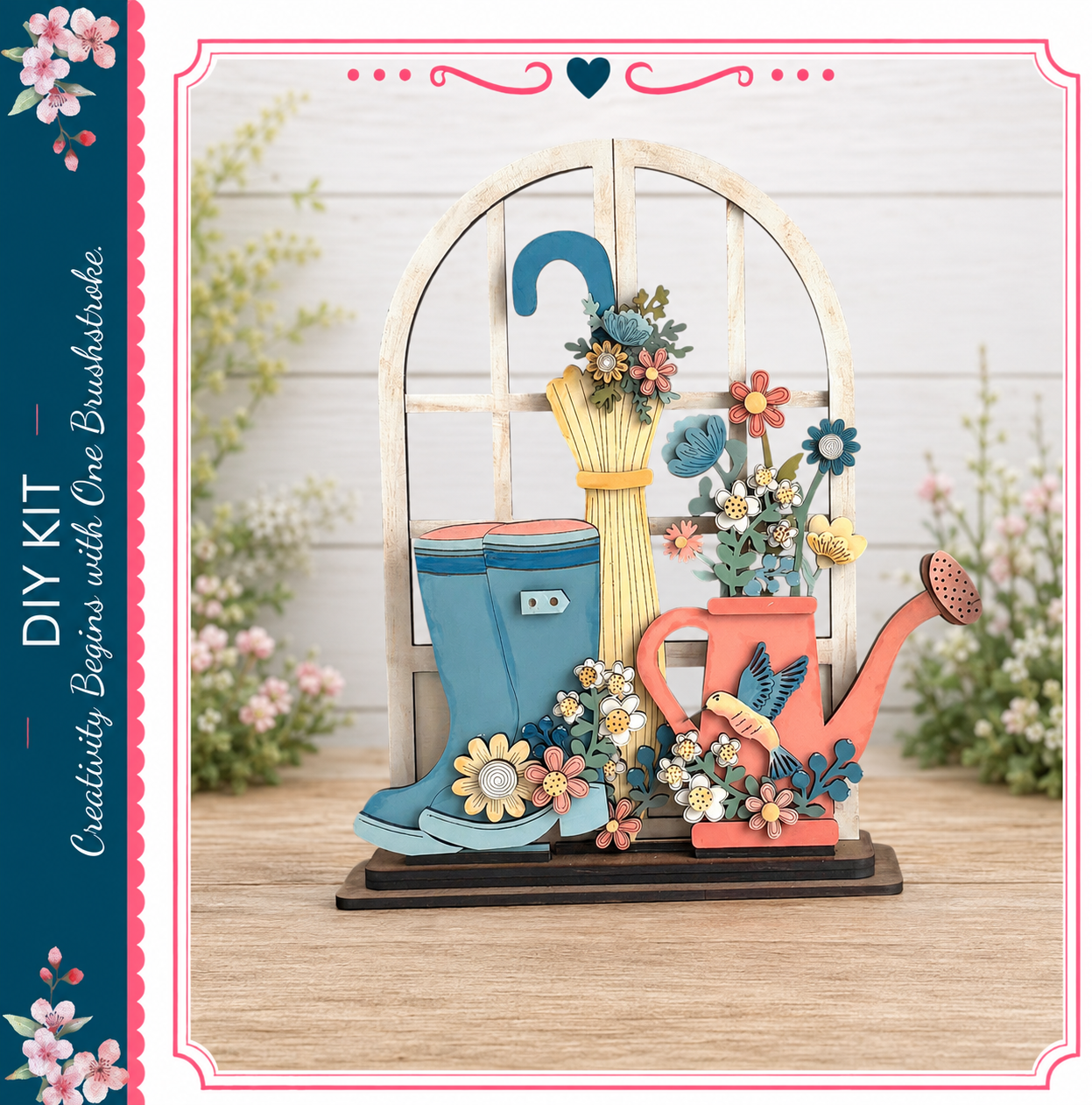 A decorative wooden display featuring a pair of blue rain boots, a yellow umbrella, and a red watering can, all adorned with colorful flowers and leaves.
