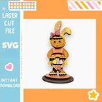 a wooden toy bunny wearing a pink dress and bow, standing on a black base.