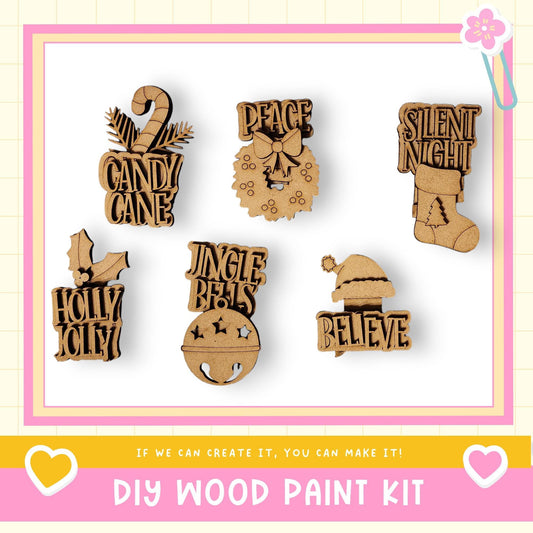 a DIY wood paint kit with various wooden ornaments and decorations, including a candy cane, peace sign, jingle bells, holly, Santa hat, and a "believe" sign.