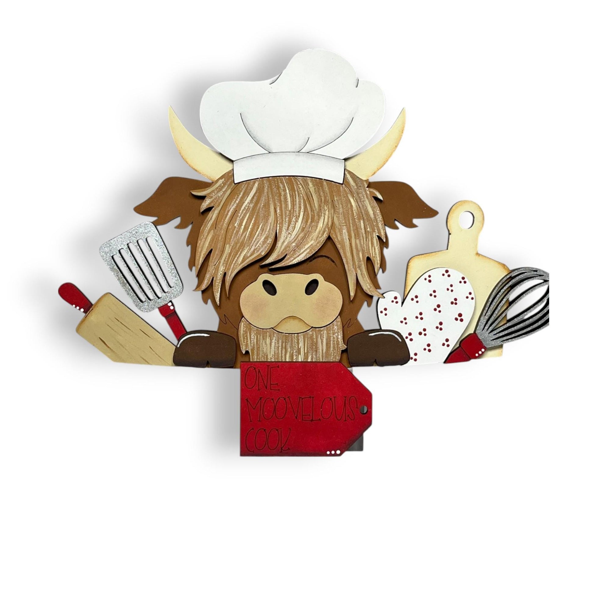 A wooden cutout of a cow wearing a chef's hat and holding a sign that says "One Moovelous Cook!"