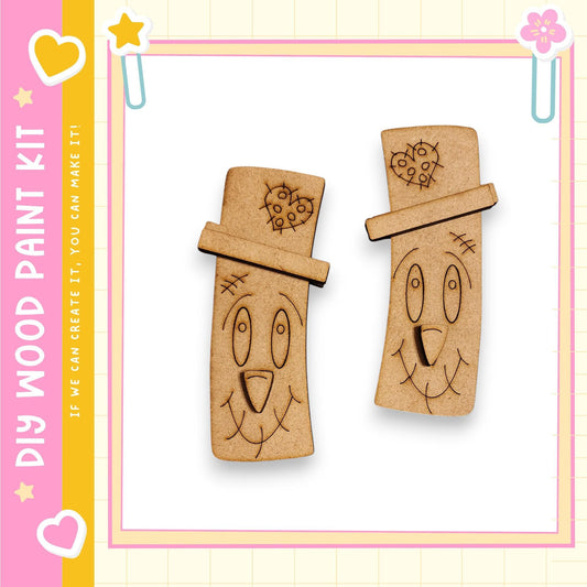 two wooden cutouts with smiling faces, set against a pink and yellow background with decorative elements.