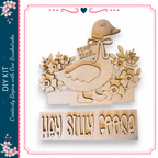 A wooden craft depicting a goose with a bow and flowers, accompanied by the text "Hey Silly Goose"