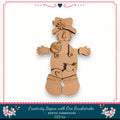A wooden scarecrow figure with a hat and a flower on its chest, standing against a white background.