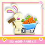 A wooden bunny holding a sign and a wheelbarrow filled with carrots, with the text "DIY WOOD PAINT KIT" and "If we can create it, you can make it!"