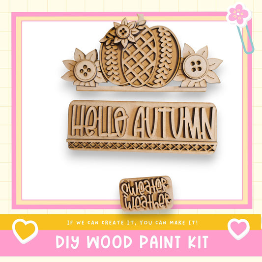 The image is a DIY wood paint kit featuring a wooden sign with the word "Hello Autumn" and a wooden cutout of a flower. The kit appears to be made of wood and is designed for creating custom signs and decorations.