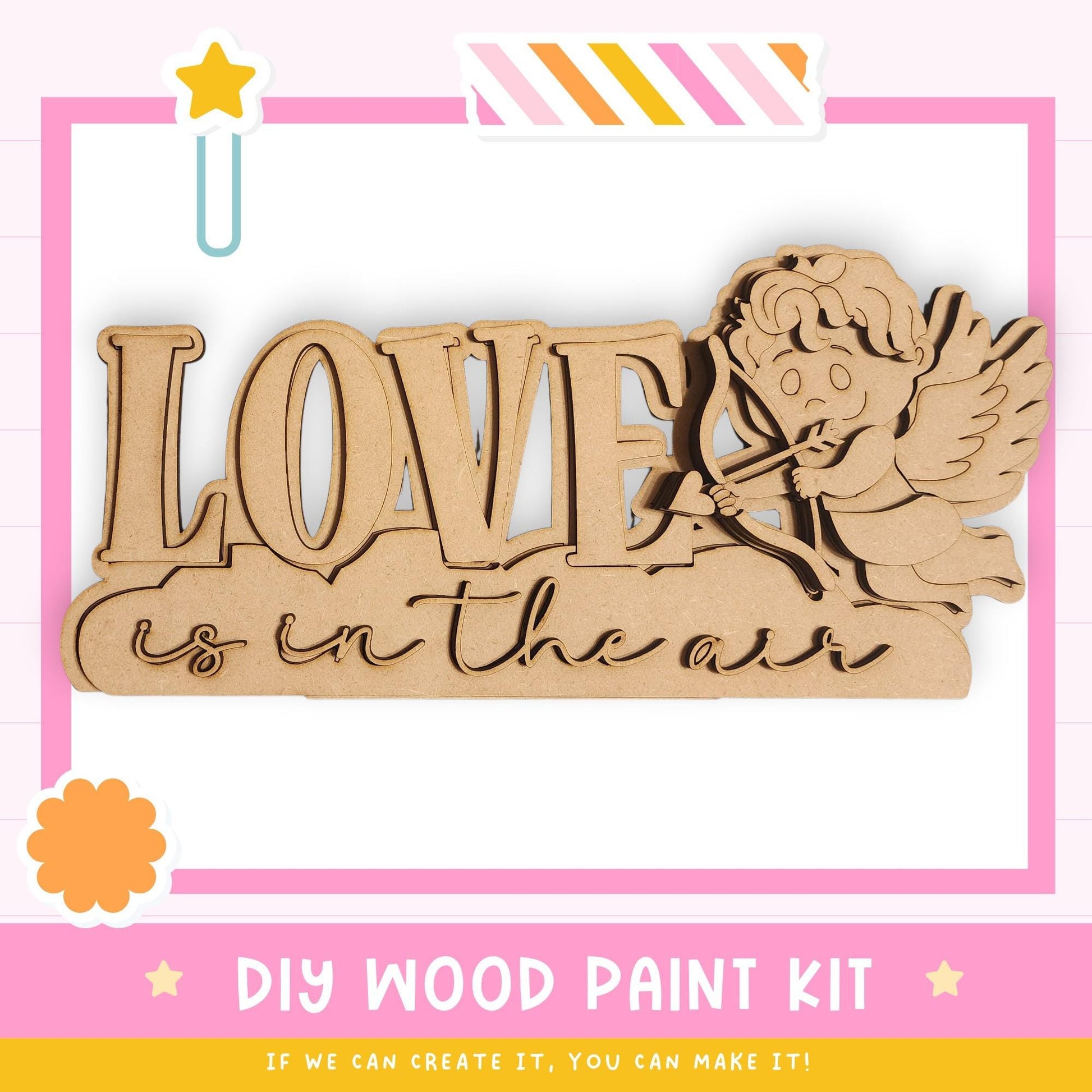 The image is a promotional poster for a DIY wood paint kit. It features a wooden sign with the word "LOVE" written on it, along with a cute cartoon character resembling a cherub or angel. The poster emphasizes that the kit allows for creativity and encourages viewers to create their own designs.