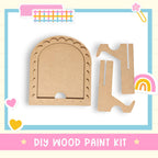 The image is a DIY wood paint kit, featuring a wooden frame and two wooden pieces, one of which is a wooden cutout. The kit is presented in a colorful and playful manner, with the text "DIY WOOD PAINT KIT" displayed prominently.
