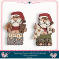 two wooden Santa Claus figurines, one wearing green pants and the other wearing red pants, holding various holiday-themed items such as a gingerbread man, a teddy bear, and a book.