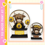 a wooden paint kit with a design of a cow and sunflowers. The kit includes a wooden base and a wooden frame, and it is described as a kit for creating wooden paint pieces.