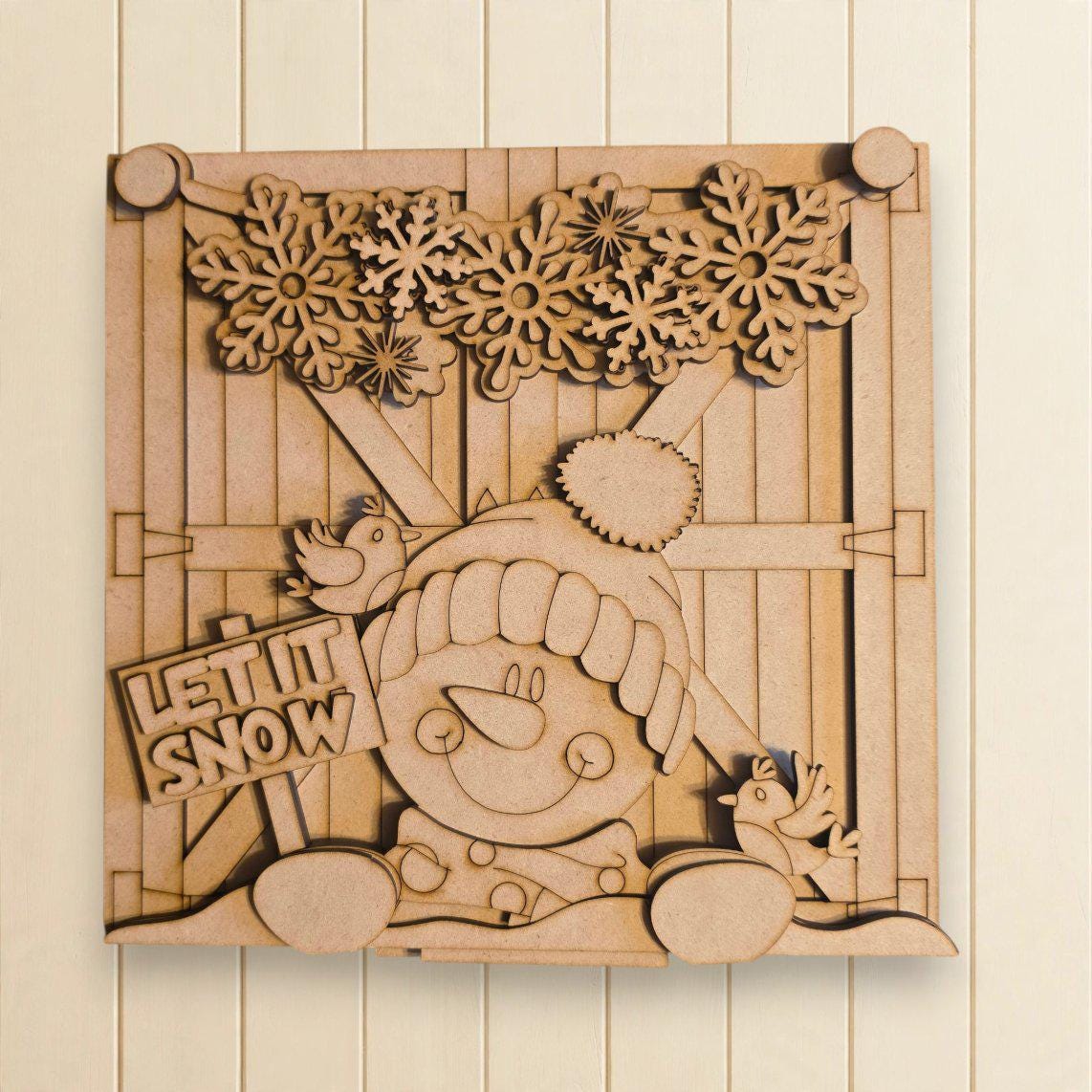 A wooden cutout of a snowman with a sign that says "LET IT SNOW" is displayed on a wall.