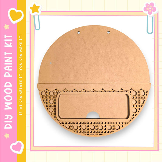 a wooden paint kit with a round, empty wooden piece and a decorative pattern on it, set against a pink and yellow background with a heart and star motif.
