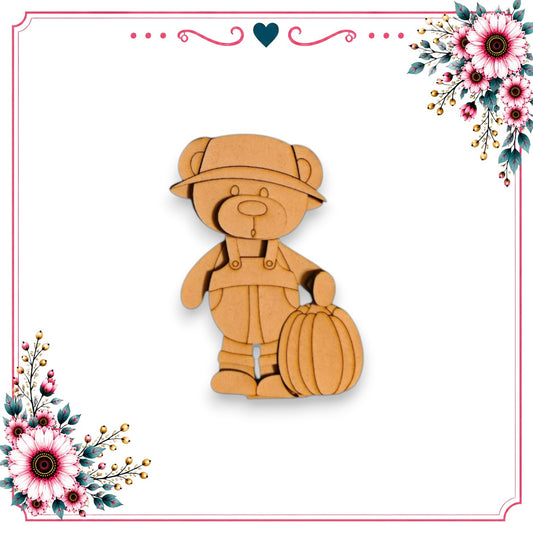 A wooden teddy bear wearing overalls and carrying a pumpkin, set against a white background with floral decorations on either side.