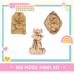 The image is a DIY wood paint kit featuring three wooden ornaments, including a deer, a heart, and a rainbow.