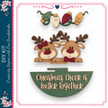 a festive scene with two wooden reindeer wearing bows, surrounded by Christmas lights and a green sign that reads "Christmas Cheek is better together".