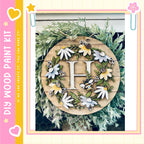 A decorative wreath made of wood and adorned with various flowers and leaves, including a large letter "H" in the center.