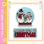 A snowman and two snowmen figures are displayed on a blue background, with a sign below that reads "DAYS UNTIL CHRISTMAS".