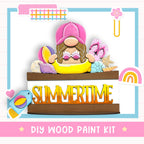 The image is a colorful and whimsical illustration featuring a gnome-like character surrounded by various summer-themed objects, such as a beach ball, flip flops, and a rainbow. The text "DIY WOOD PAINT KIT" is prominently displayed, indicating that this is a DIY wood paint kit for creating a summer-themed artwork.