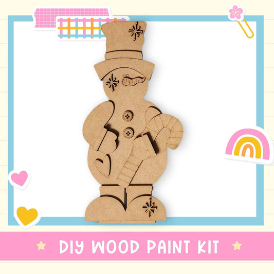 A DIY wood paint kit for creating a snowman, featuring a wooden figure with a hat, scarf, and carrot nose.