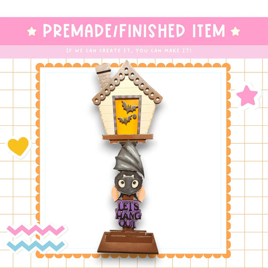 a Halloween-themed decoration, including a bat-shaped house and a sign that says "Let's Hang Out!".