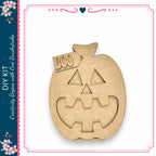 A wooden pumpkin with a carved face and the word "BOO" on it, displayed against a white background.