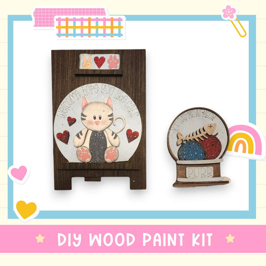 The image is a DIY wood paint kit featuring a wooden frame with a cat design and a small wooden figurine of a cat. The kit includes a wooden frame and a wooden figurine, both with cat designs. The kit is labeled as a "DIY WOOD PAINT KIT".