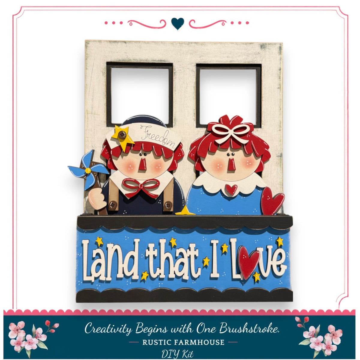 A wooden frame with two small figures, likely representing two children, and the phrase "Land that I Love" written on it. The frame appears to be a creative DIY kit, possibly for a rustic farmhouse theme.