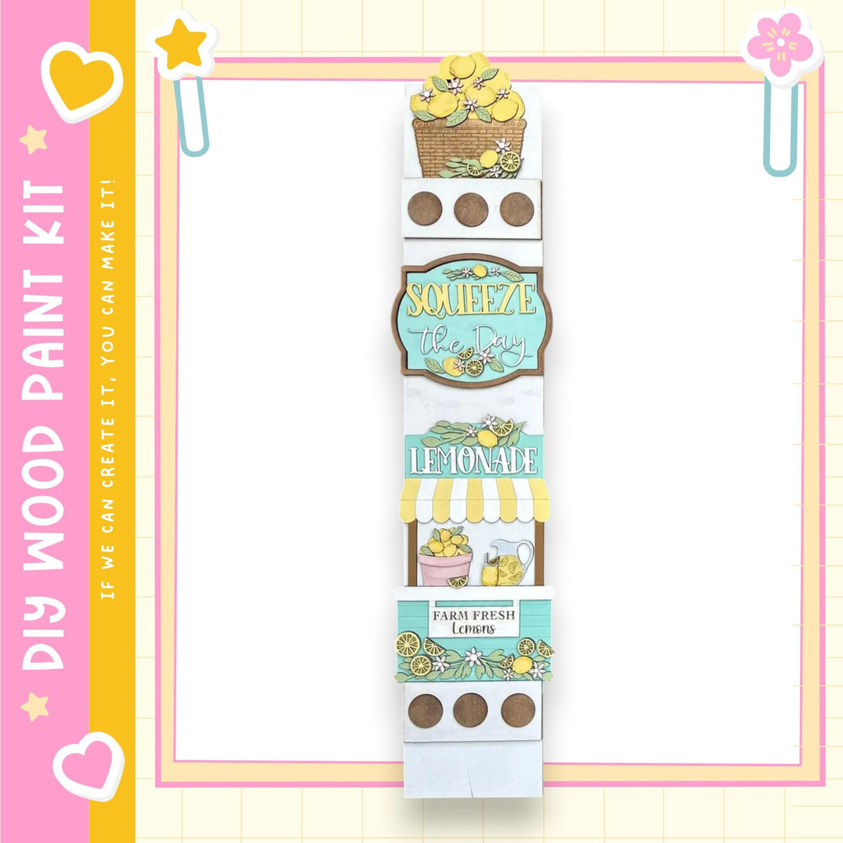 A vertical display featuring a lemonade sign, lemonade glasses, and a basket of lemons, all set against a pink and yellow background.