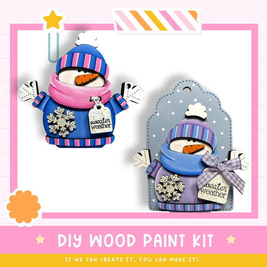 The image is a DIY wood paint kit for creating wooden snowmen. It features two wooden snowmen with colorful winter clothing and accessories, such as scarves, hats, and snowflakes, as well as a sign that says "Winter weather".