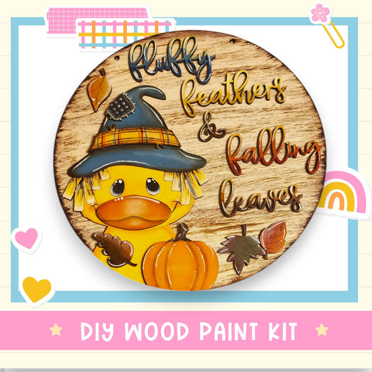A wooden sign with a cartoon duck wearing a witch's hat and holding a pumpkin, surrounded by autumn leaves and a rainbow.