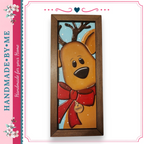 A wooden picture frame with a painted reindeer wearing a red bow and a tag that says "PANIEK". The reindeer has antlers and is looking directly at the camera.