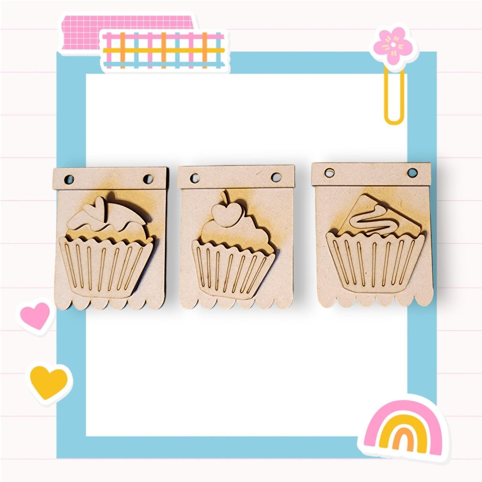 three wooden cutouts of cupcakes with a rainbow in the background