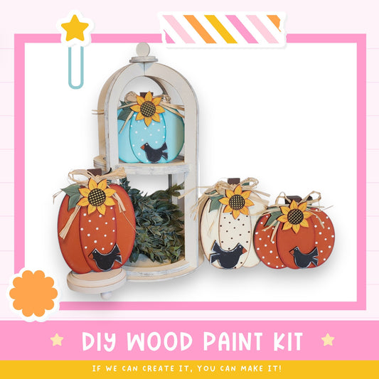 a DIY wood paint kit for creating wooden pumpkins, with four wooden pumpkins displayed in a white wooden frame.