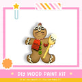A wooden gingerbread man figure with a red tag that says "Christmas Donuts" and a heart-shaped button on its chest, set against a pink and white background.