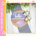 a wooden sign with the word "Hello" written on it, surrounded by decorative elements such as a ribbon and a plant. The sign is placed on a wooden surface, and there are some plants and a pink heart visible in the background.