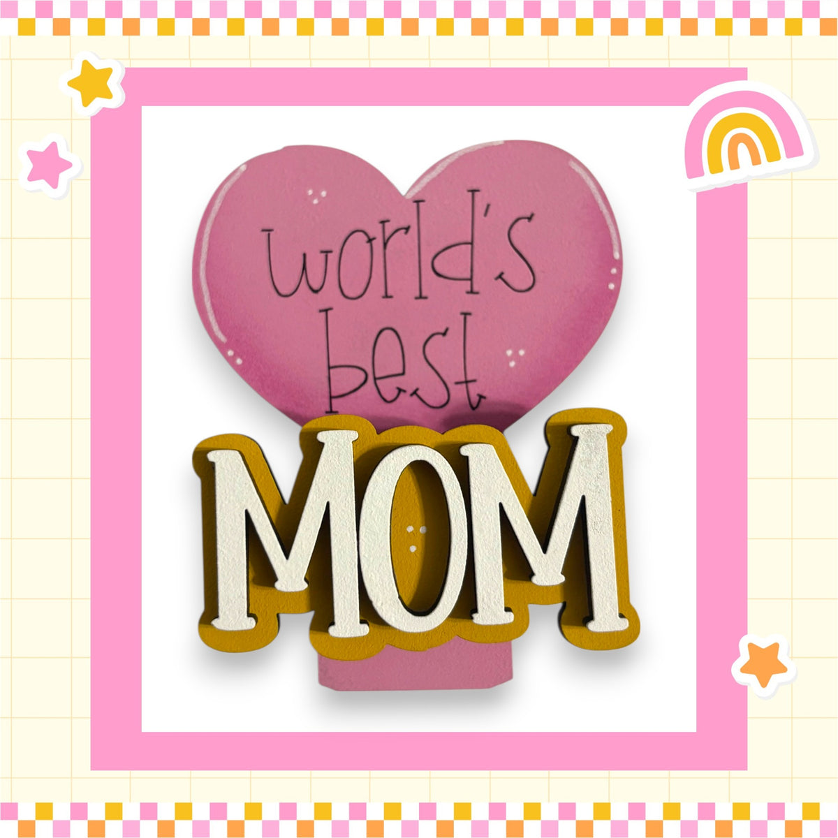 a pink heart-shaped sign with the text "world's best mom" written on it, surrounded by a pink and yellow checkered border.