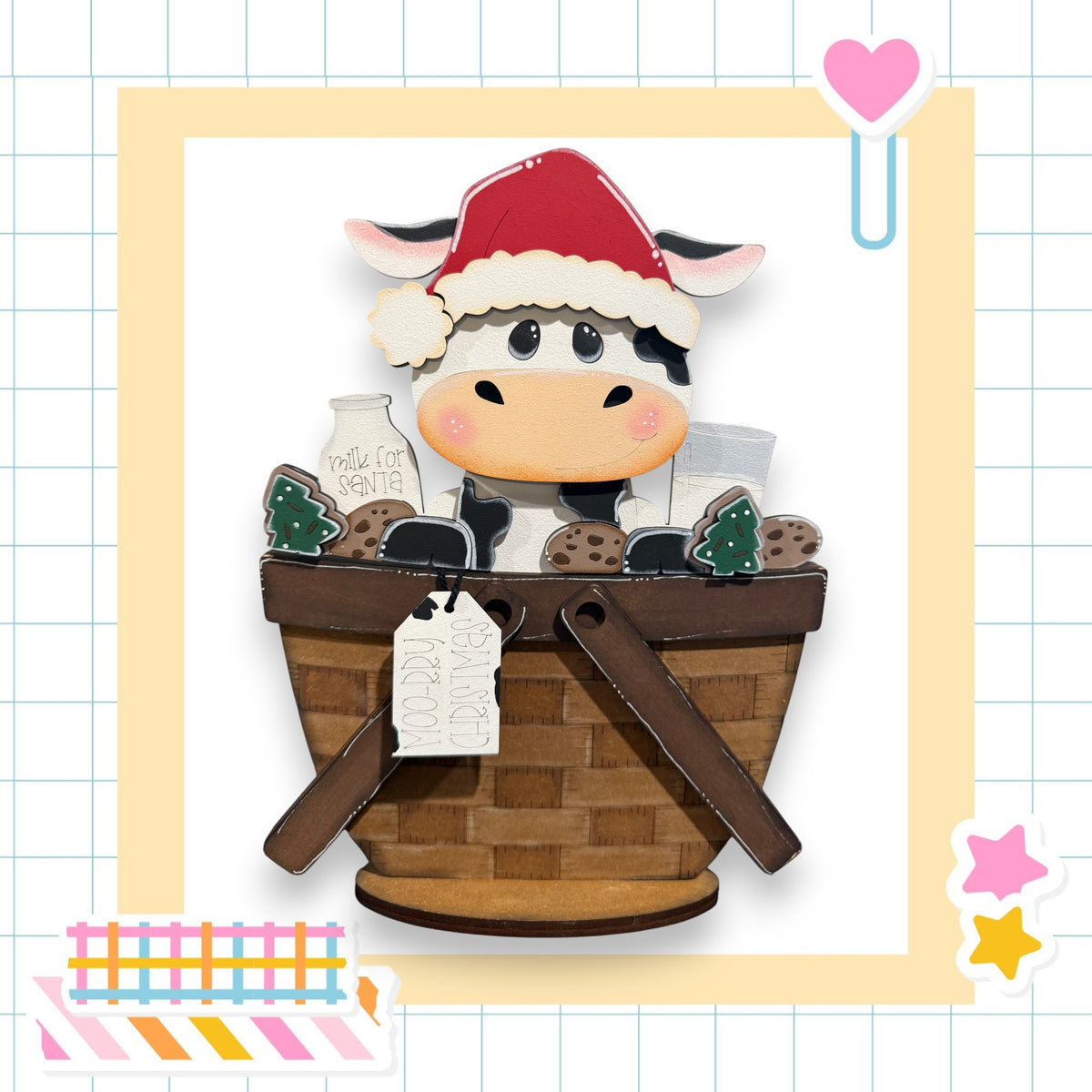A wooden cow wearing a Santa hat sits in a basket filled with various items, including a milk carton and cookies.