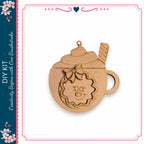 A wooden ornament in the shape of a cup with a smiley face and a wreath on top, sitting on a white background.