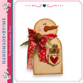 A handmade snowman decoration with a red scarf, bell, and heart-shaped ornament, set against a white background.