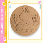The image is a circular wooden craft kit featuring a design of a rabbit's feet and a flower.