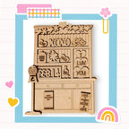 a wooden cutout of a kitchen with a rainbow in the background