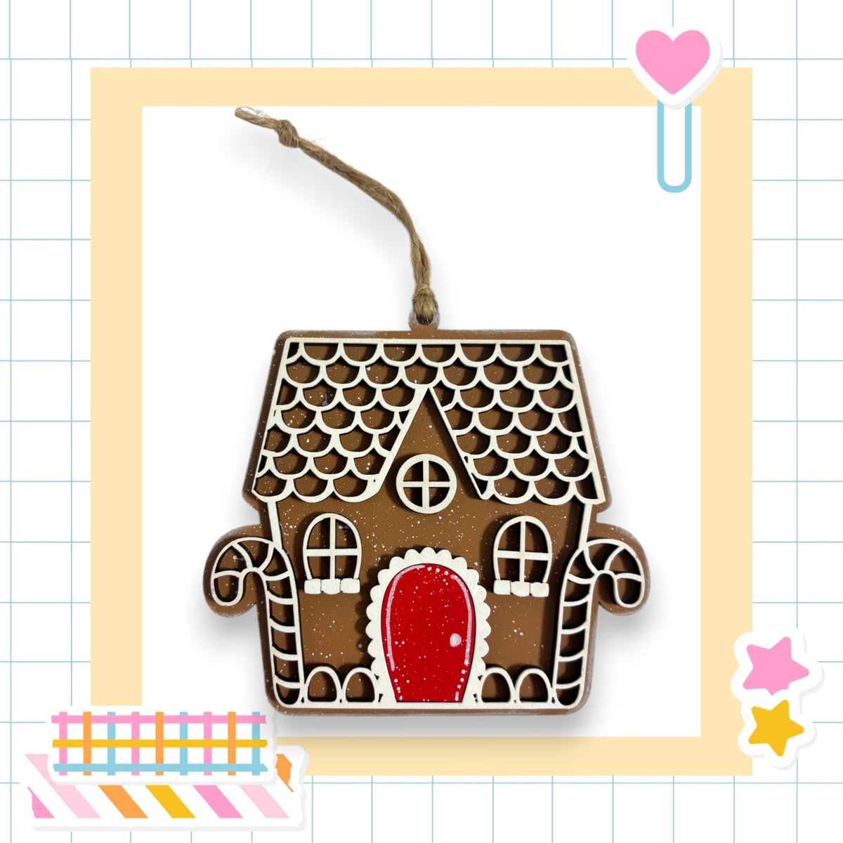 A wooden gingerbread house ornament with a red door and windows, hanging from a string.