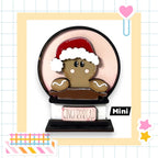 A gingerbread man wearing a Santa hat and holding a sign that says "Gingerbread" is the main focus of the image.
