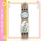The image is a colorful and decorative wooden frame with various floral and bird-themed elements, including a heart, flowers, and a bird. The frame appears to be a creative and artistic piece, possibly used for scrapbooking or as a decorative item.