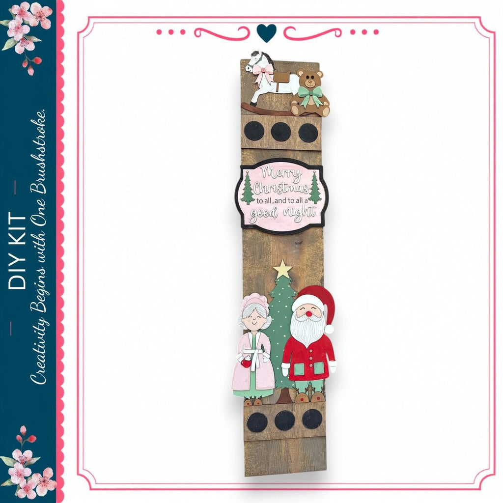 The image is a festive DIY kit featuring a wooden panel with a Christmas tree, Santa Claus, and a teddy bear. The panel also includes a message that reads "Merry Christmas to all and to all a good night".