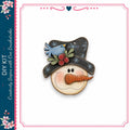 A wooden snowman with a carrot nose and a blue bird perched on its hat, set against a white background.